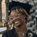 Taylor Rutledge is a black woman with natural curls, glasses, wearing her UCF graduation apparel
